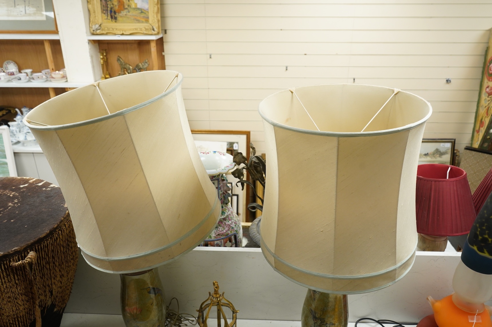 A pair of table lamps and shades, 92cm high, the lamps decorated in gold and green tones painted with birds and flowers, together with a small glass and brass hall lantern (3).